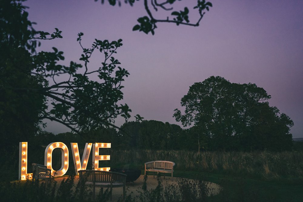 Light up love letters next to the fire pit at a micro wedding outdoors