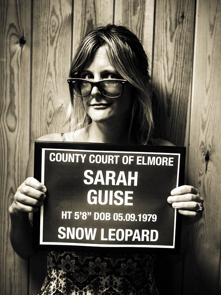 Anselm Guise's wife Sarah of stately home Elmore Court pictured in funny black and white mugshot photo holding up joke sign