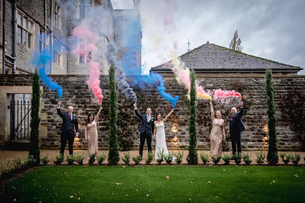 Micro wedding guests celebrate with colourful smoke bombs in the grounds of wedding venue elmore court in 2020