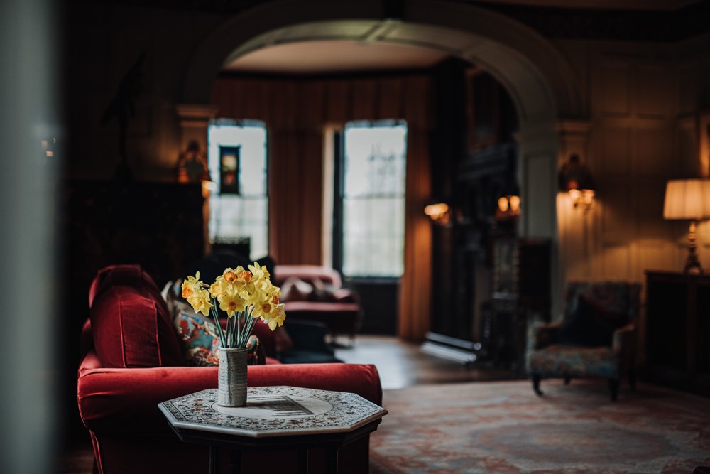 Cosy drawing room in a mansion house with daffodils in a vase at a gay wedding