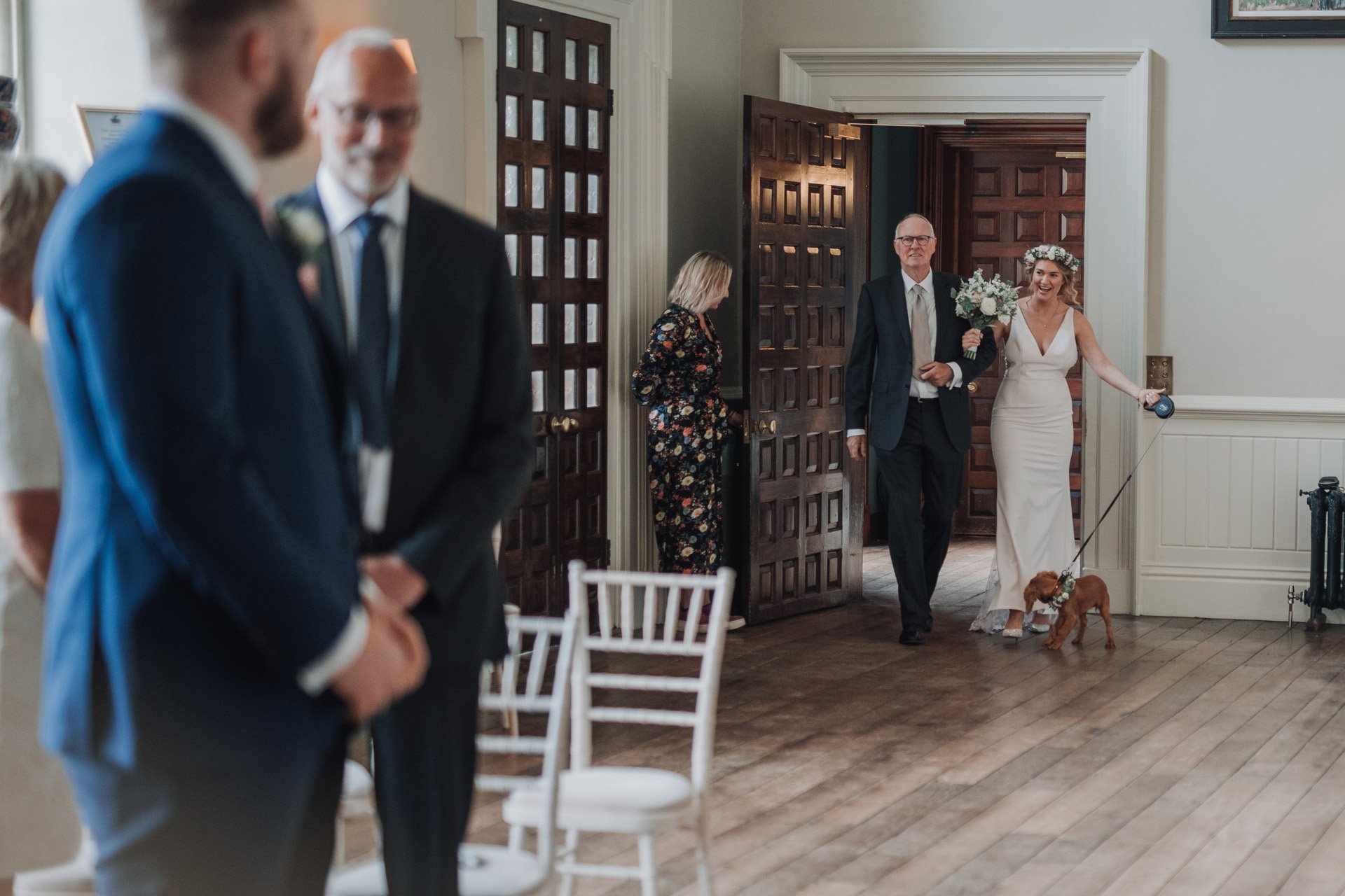 Here comes the bride with puppy bridesmaid wearing flowers at elmore court covid micro wedding