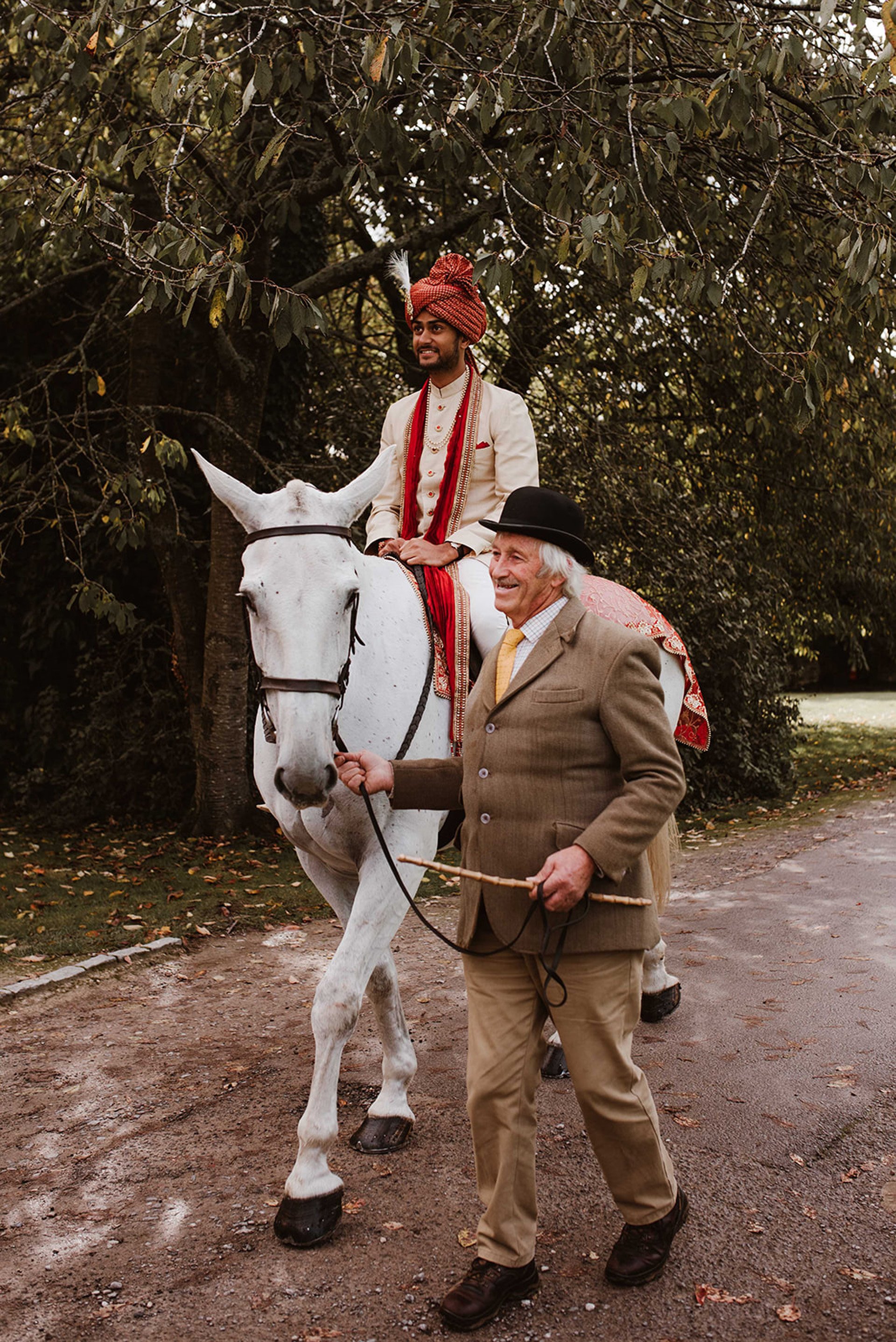 Indian groom arrives on horse back as part of the baraat procession and party at indian wedding venue 