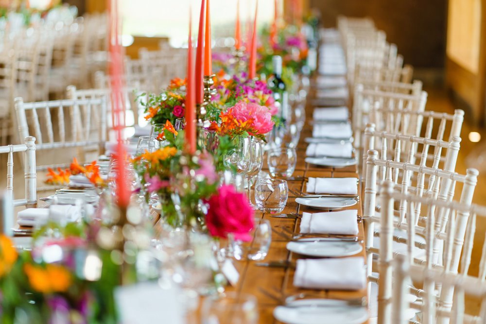 Bright pink and orange wedding table decor with flowers and candles at Jewish wedding reception in the summer at elmore court