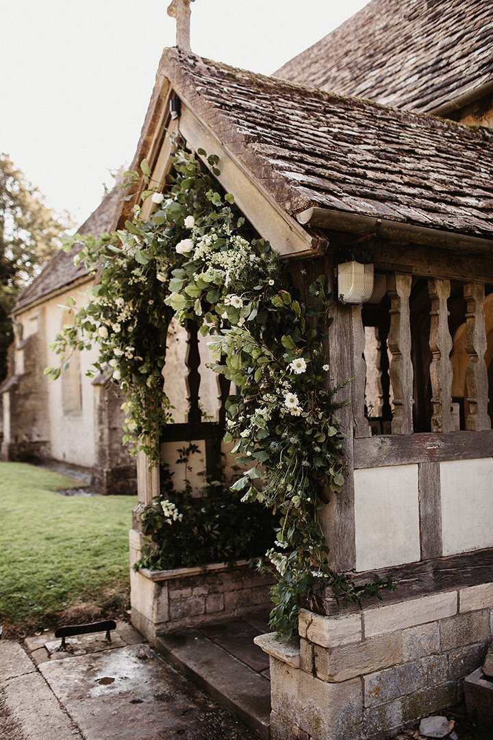 The prettiest church in England entrance decorated with greenery for a wedding at Elmore 