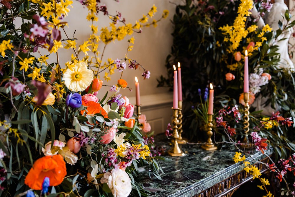 Bright yellow and orange wild spring flowers with long candles for wedding fair decoration at eco stately home elmore court