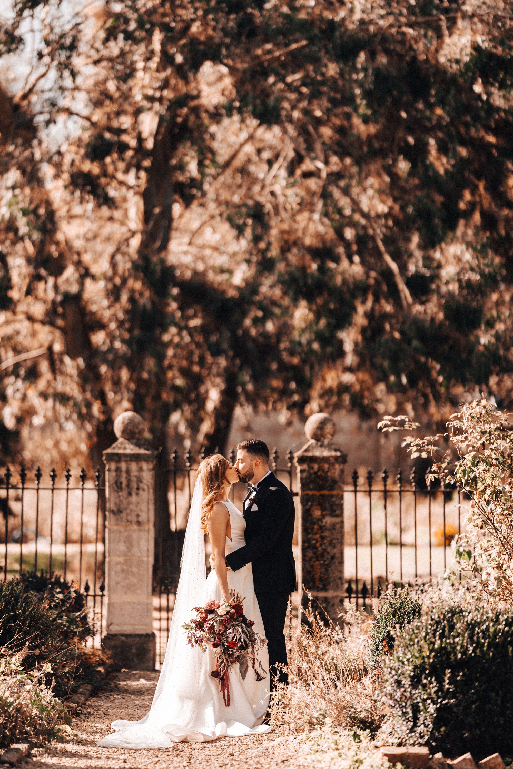 Newlywed couple kiss in autumn walled gardens of Gloucestershire wedding venue elmroe court