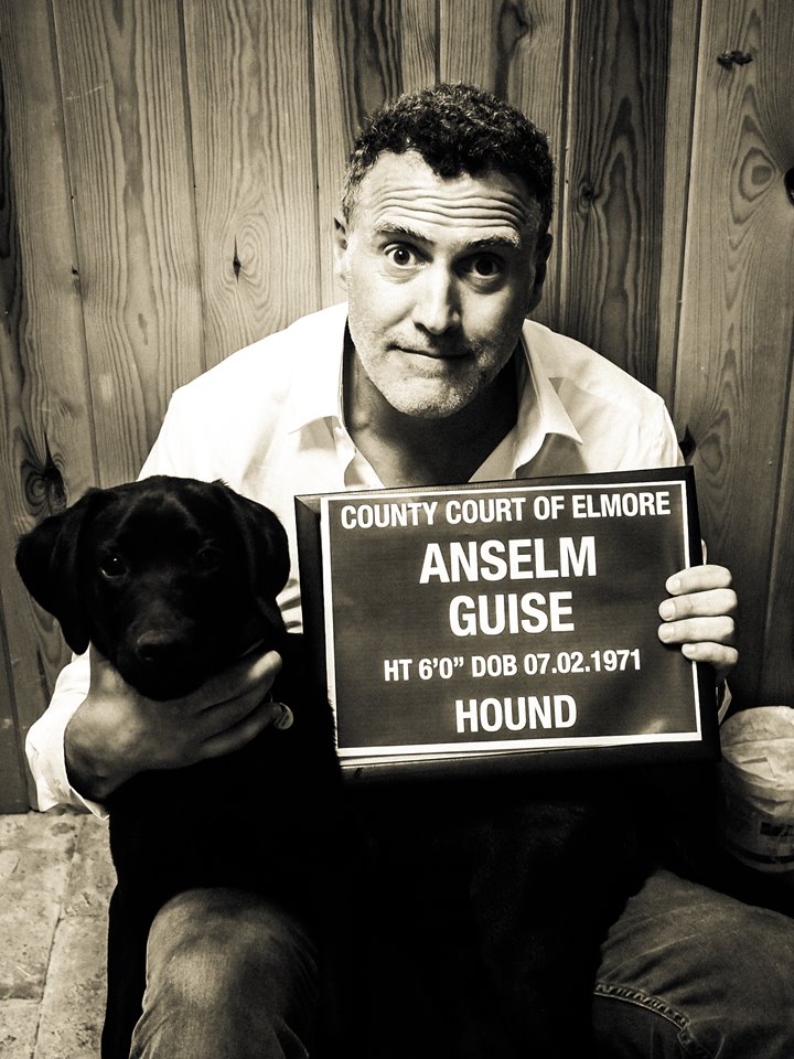 Anselm Guise of mansion house Elmore Court with his dog Charlie, holding up a joke mugshot sign for the Team E page of wedding planning site