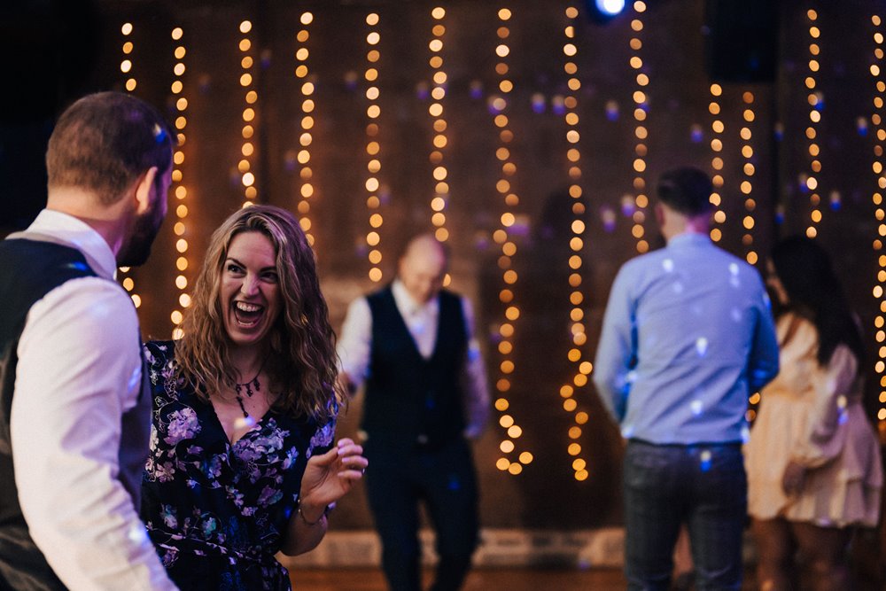 Guests having fun dancing at a magical party wedding with twinkling lights and candles in October