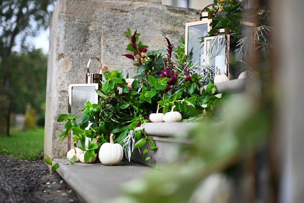 Mini white pumpkins greenery and lanterns decorate the steps to stately home halloween wedding venue