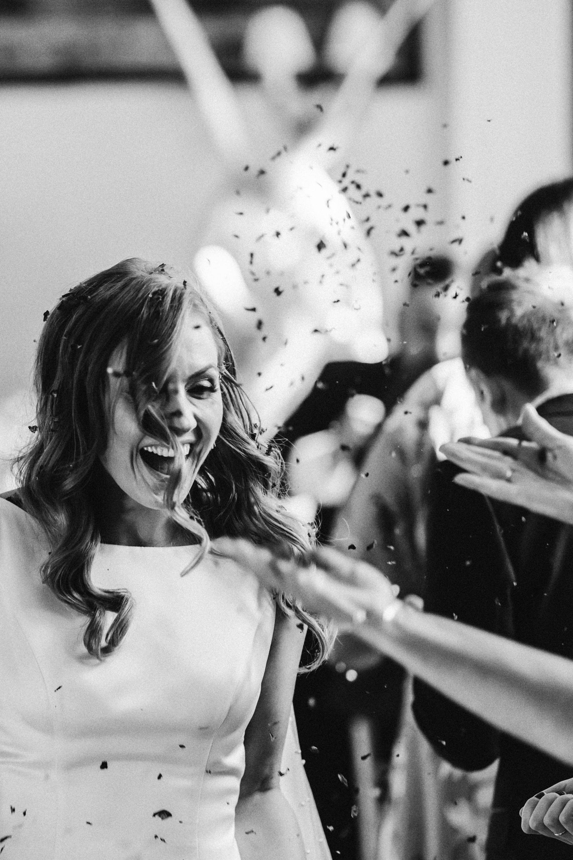 Confetti thrown at brides face as she laughs during october wedding ceremony in a cotswolds country mansion