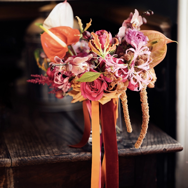 Unusual wedding bouquet with bright tropical flowers and velvet ribbon at wedding venue elmore court