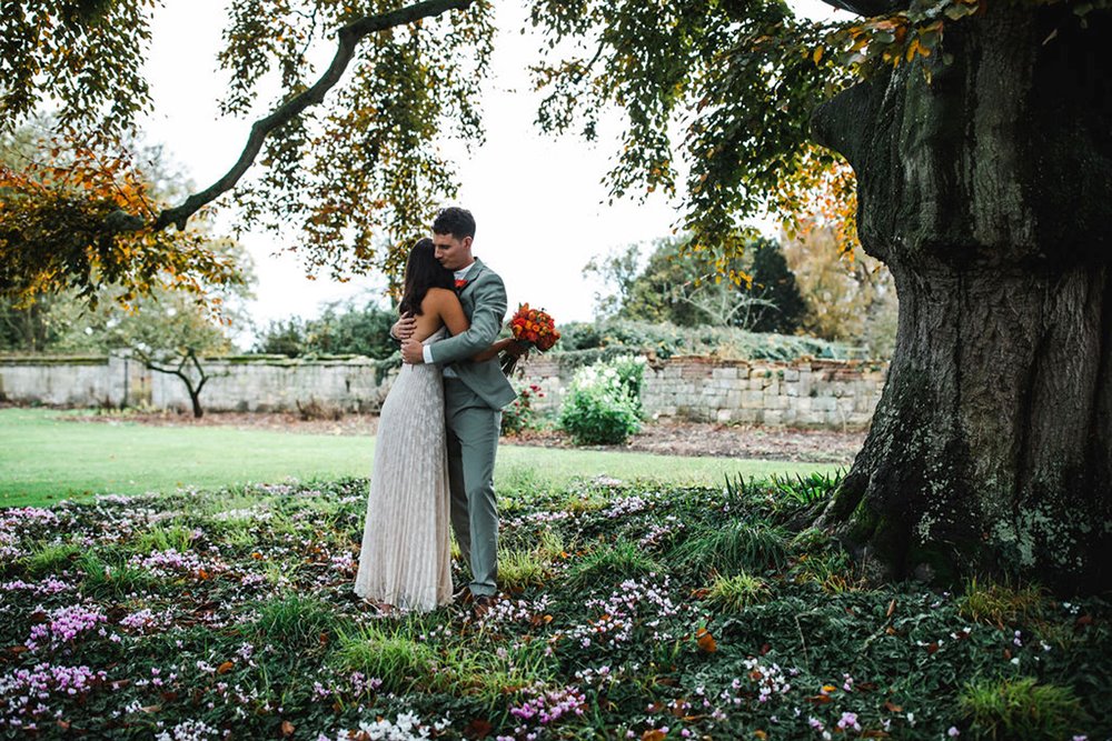 couple embrace under beech tree after just marrying at elmore court in pandemic micro wedding