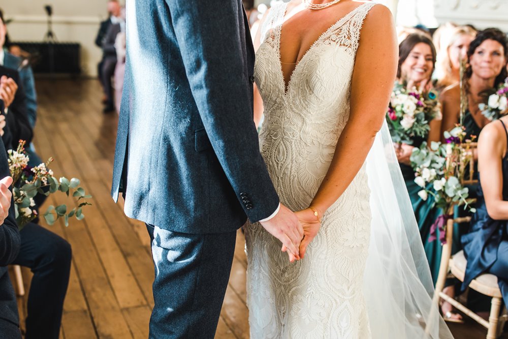 Bride and groom holding hands bride wearing 70s pattern lace wedding gown