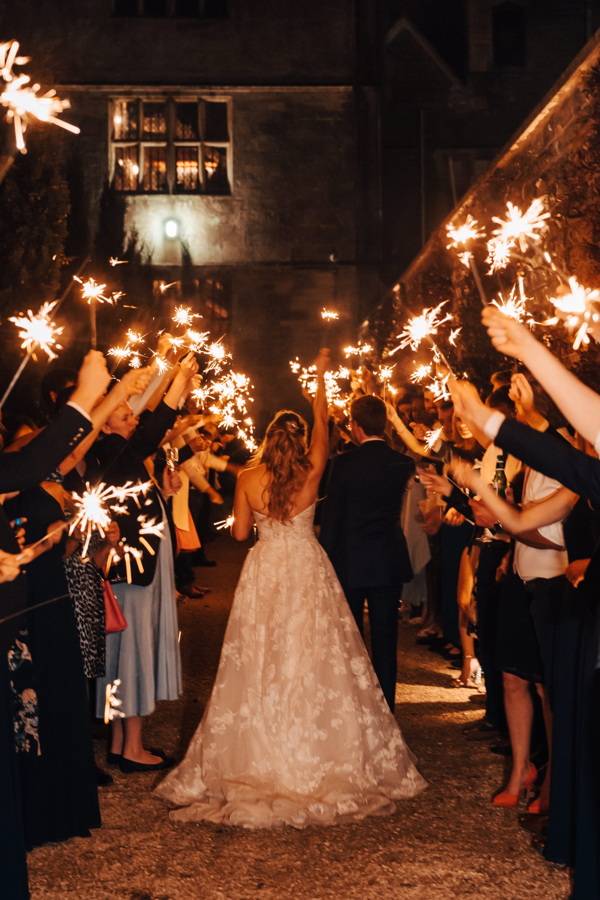 bride and groom walk down a procession of friends and family holding sparklers