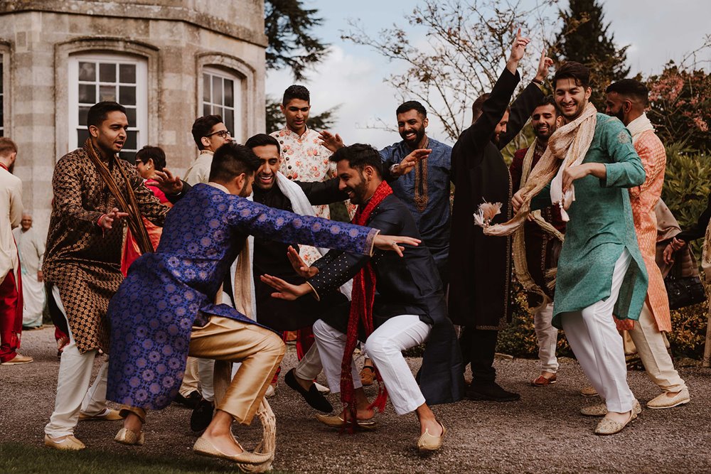 Asian men have fun dancing outside stately home wedding venue in the Cotswolds