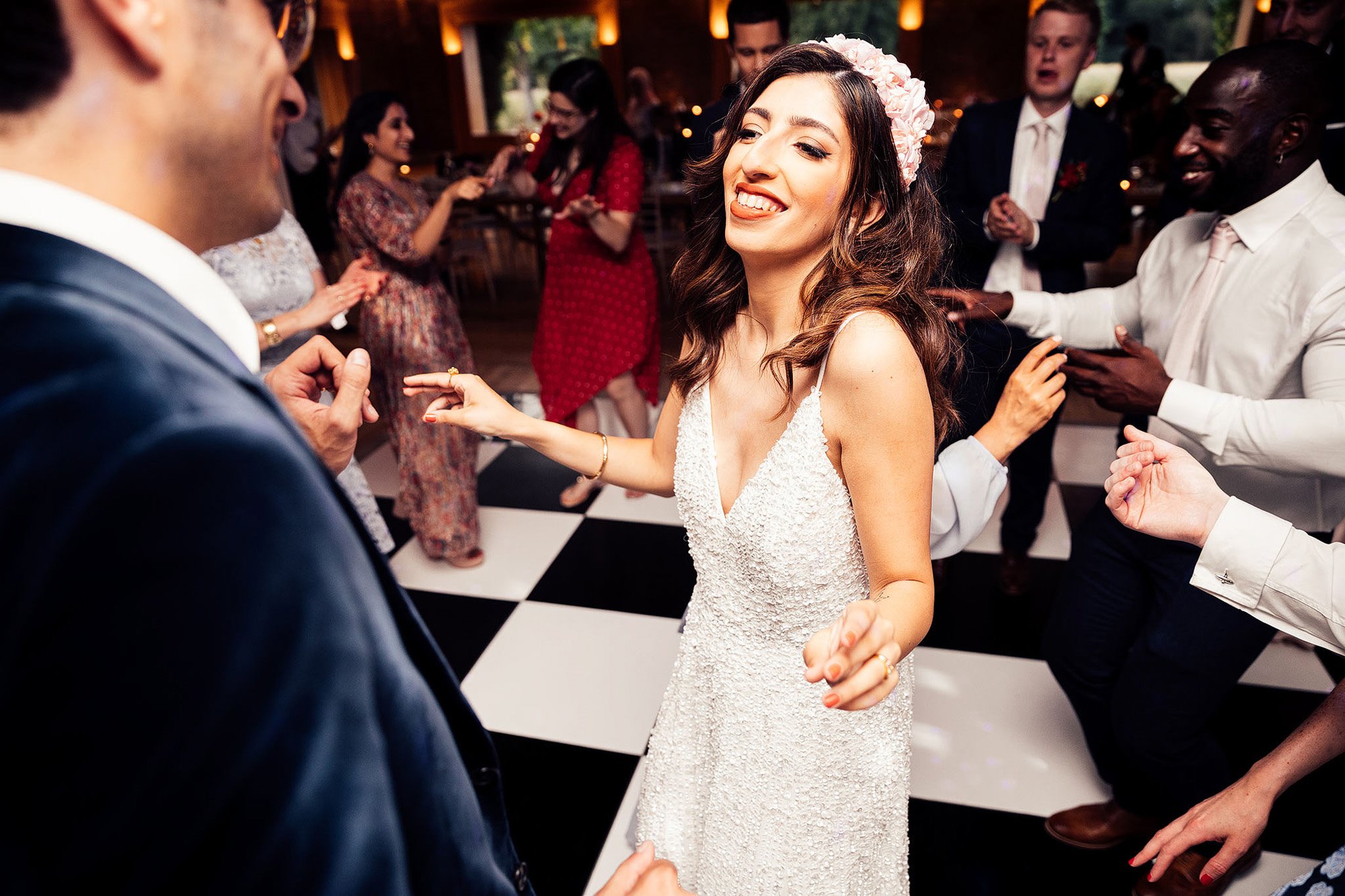 Beautiful Persian bride on check dancefloor wearing pearl dress and headpiece with groom in blue velvet suit at their party wedding