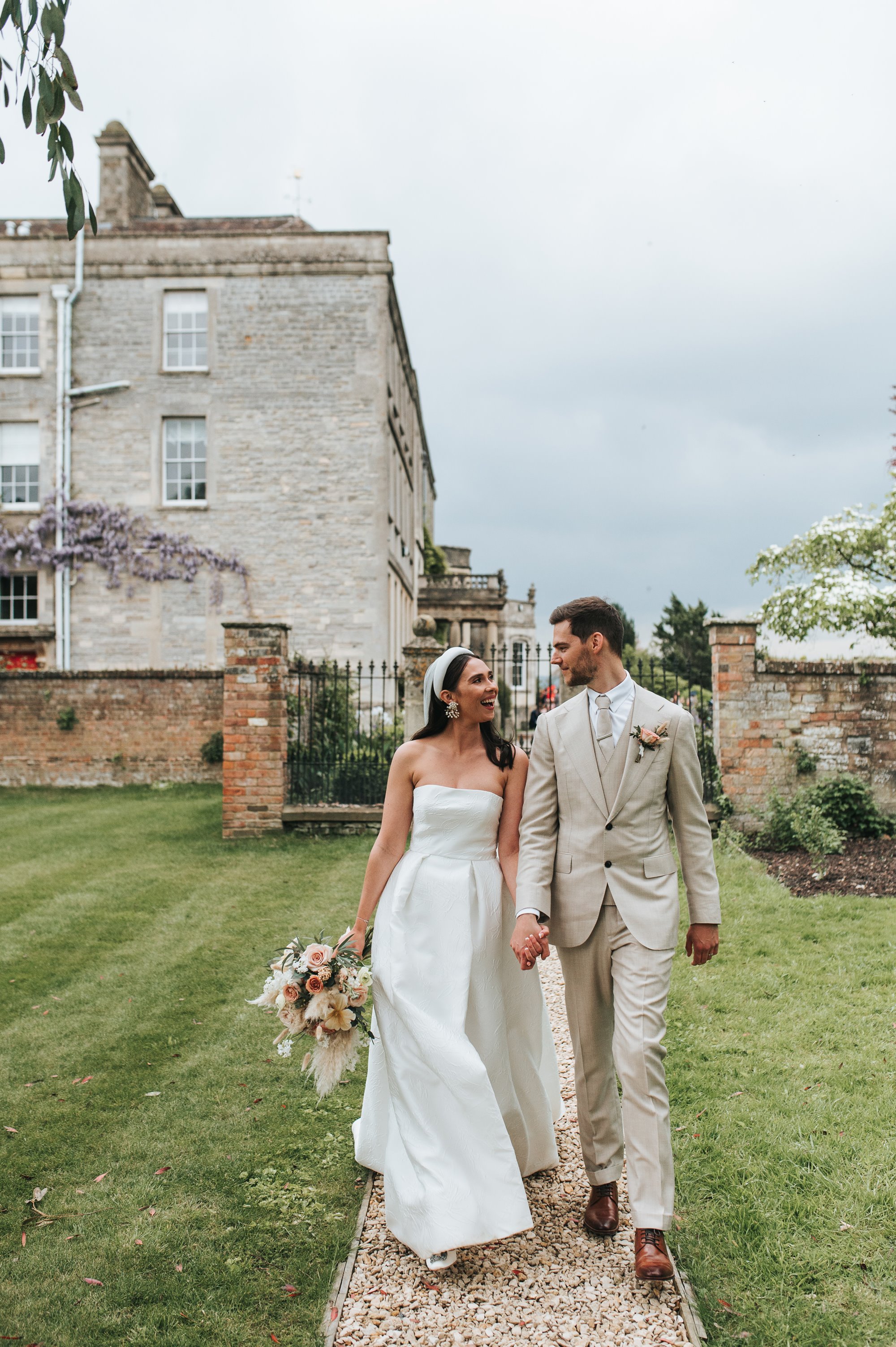 Bride and groom walking through a lovely walled garden of a stately home and wedding venue in the cotswolds