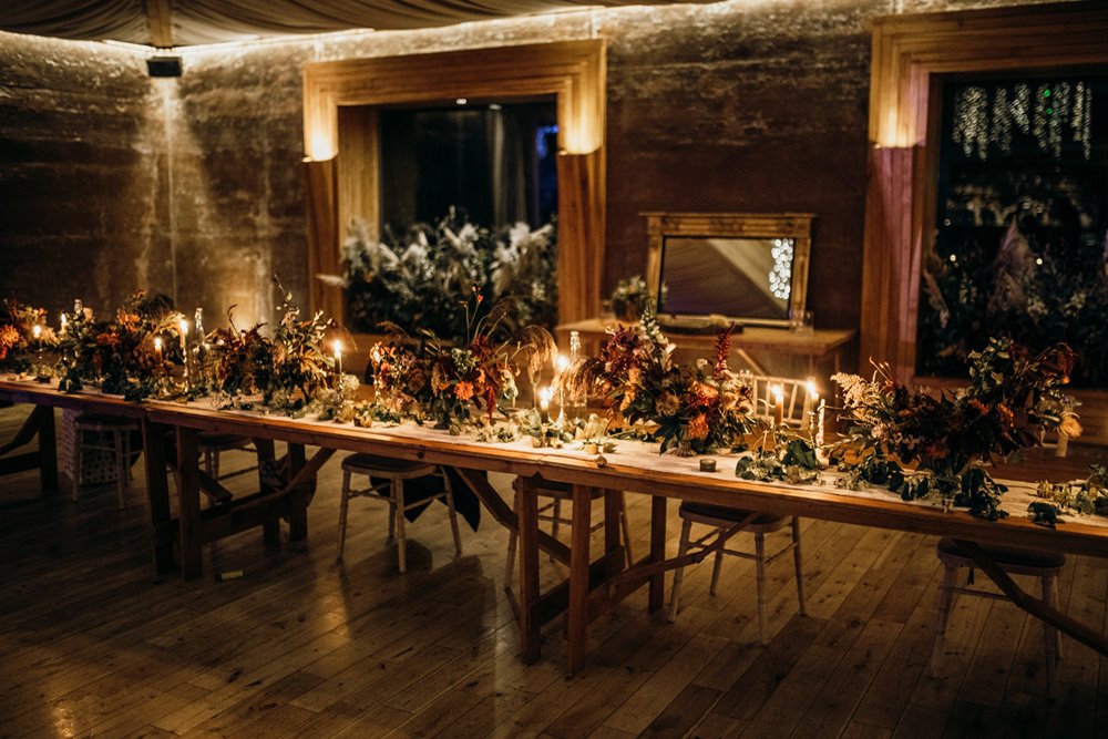 Dark wedding flowers on tables in reception venue