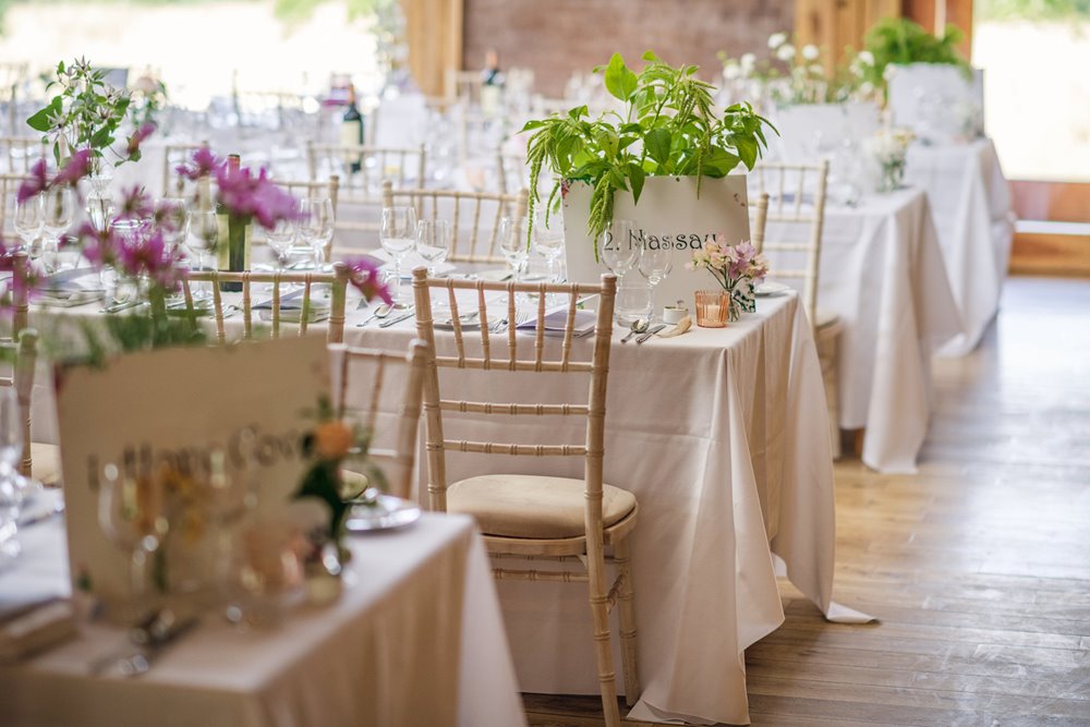 Garden party flowers adorn white linen tables for this gay wedding reception at elmore court