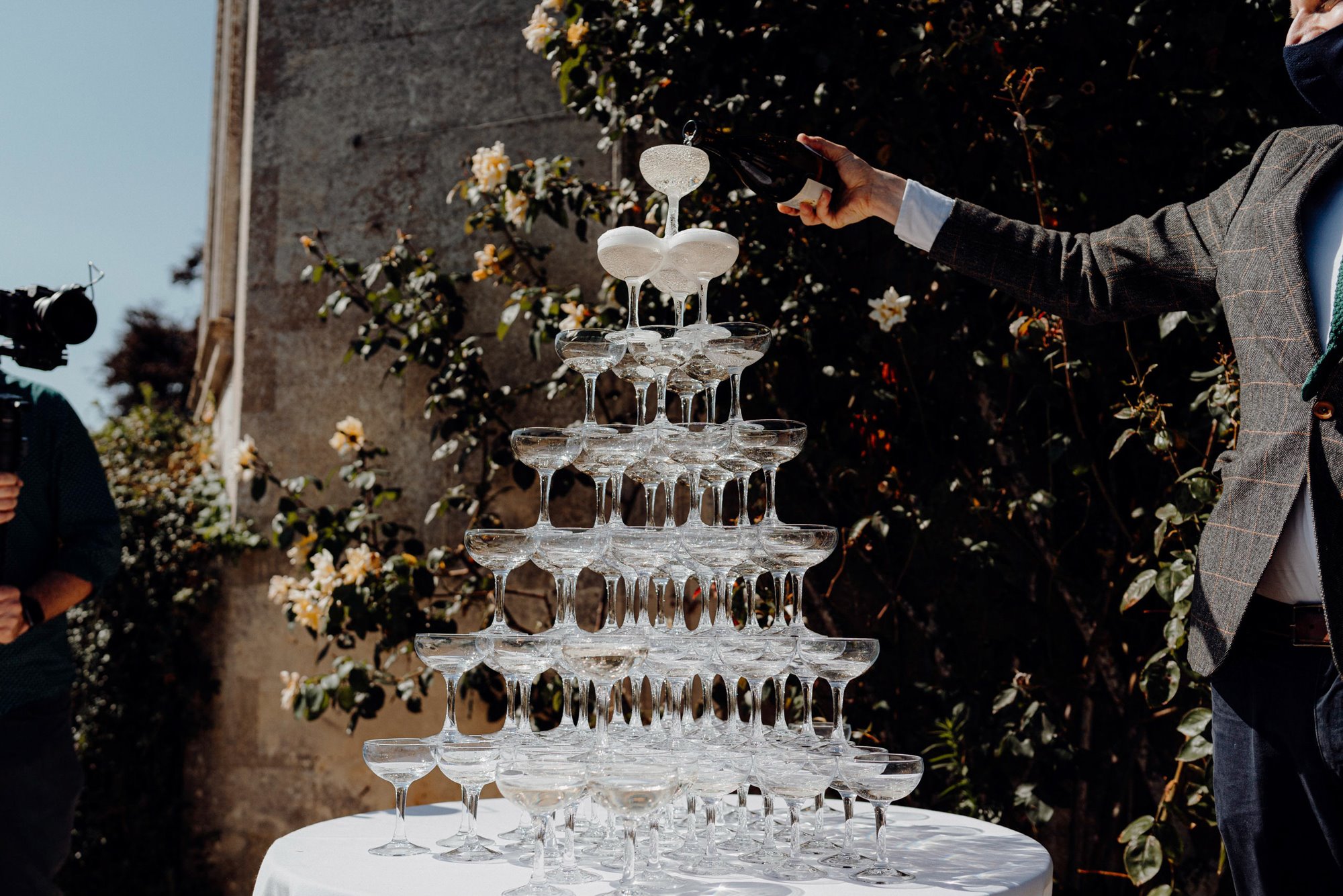 A groom pouring champagne into an impressive champagne tower at Elmore Court