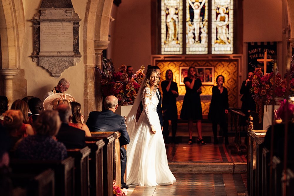 beautiful bride at the end of the aisle in a stunningly lit church, with singers in the background