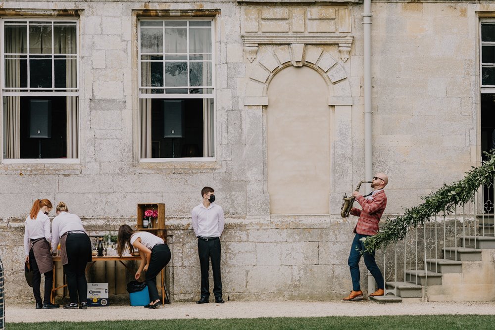 Walkabout musician plays the saxophone down the steps as a surprise festival addition to outdoor wedding 