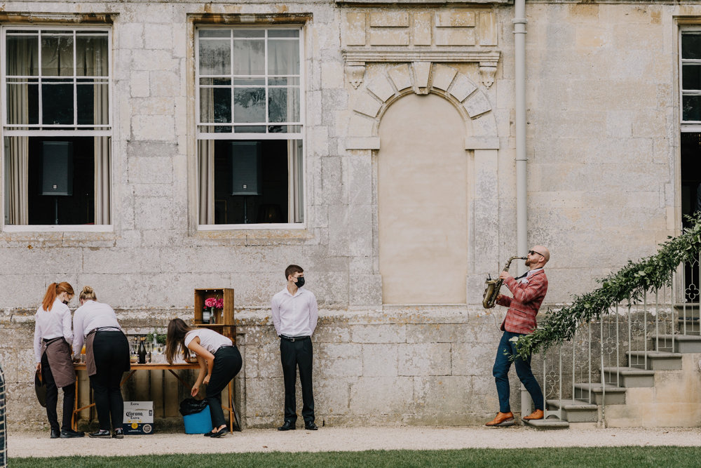 Walkabout musician plays the saxophone down the steps as a surprise festival addition to outdoor wedding