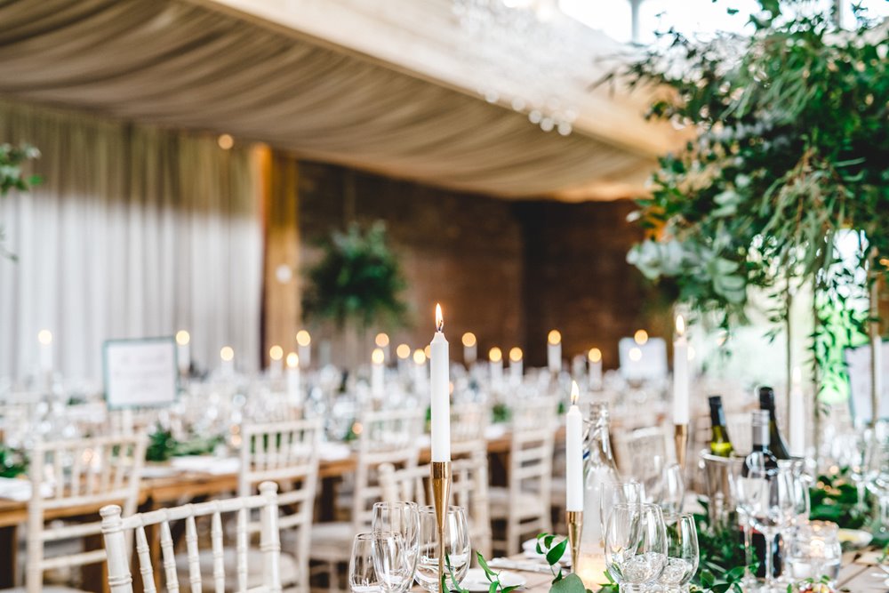 Candlelit tables with greenery for a gay wedding reception at elmore court