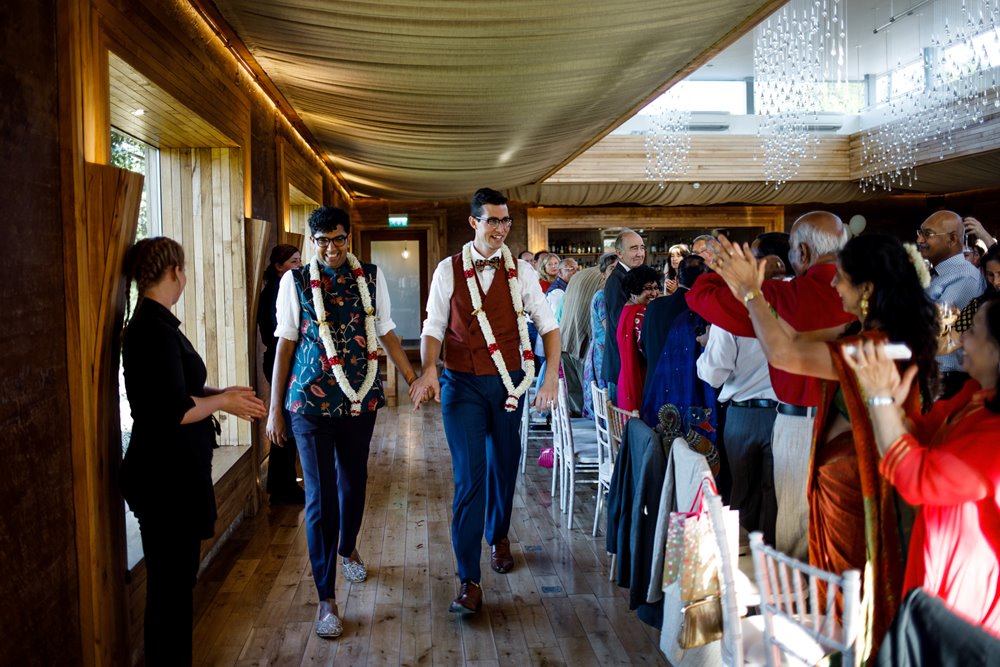 Happily married Hindu gay couple enter their reception holding hands at elmore court wedding venue in Gloucestershire