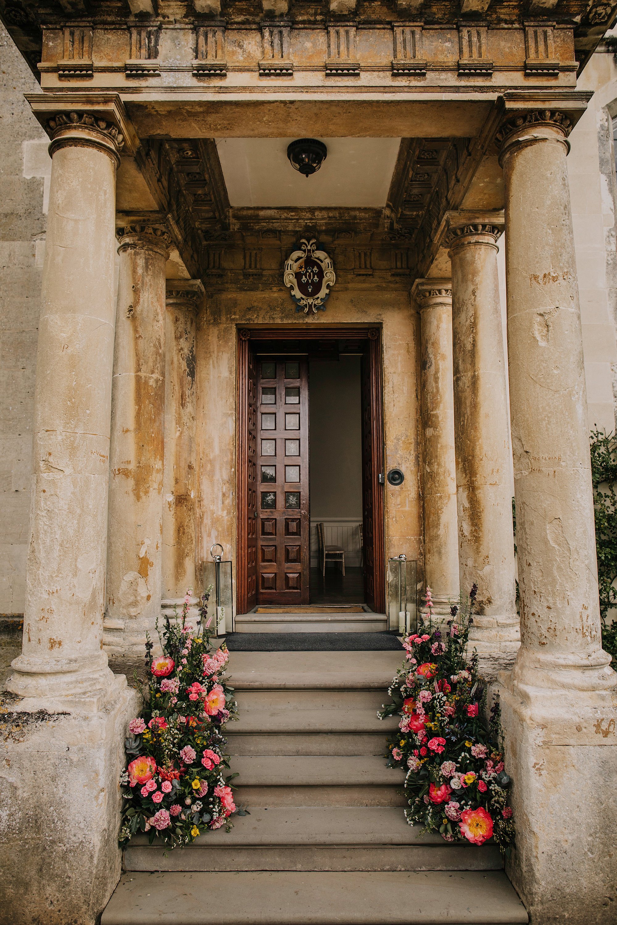 wedding florals in pink and greenery on the steps to country wedding venue elmore court