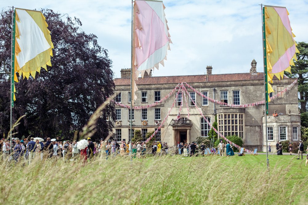 Festival wedding on the front lawn of mansion house elmore court with flags and bunting