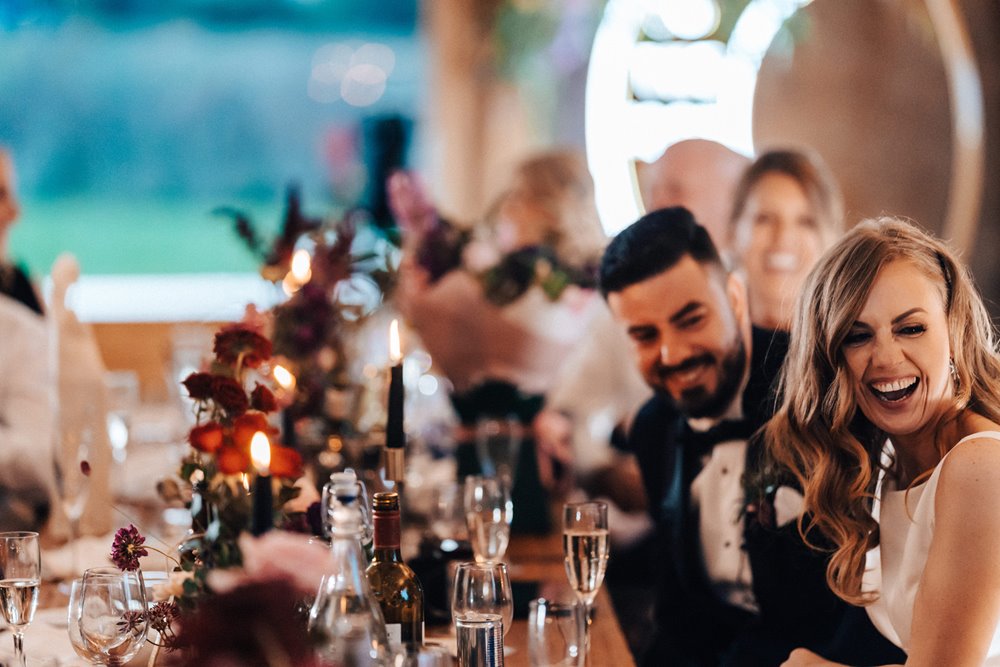 bride and groom laugh with their guests at whimsical wedding reception with black details and celestial decor for october