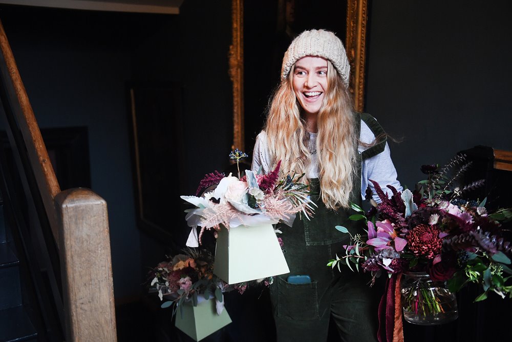 Florist brings dark autumn wedding flowers to the bride getting ready for her halloween wedding