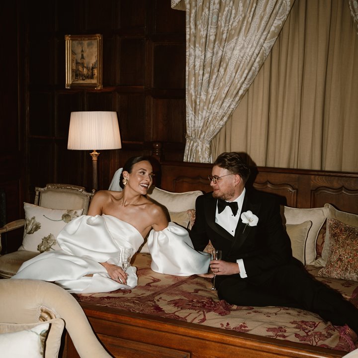 Luxe bride and groom on huge stately home bed at their luxury wedding venue in the cotswolds