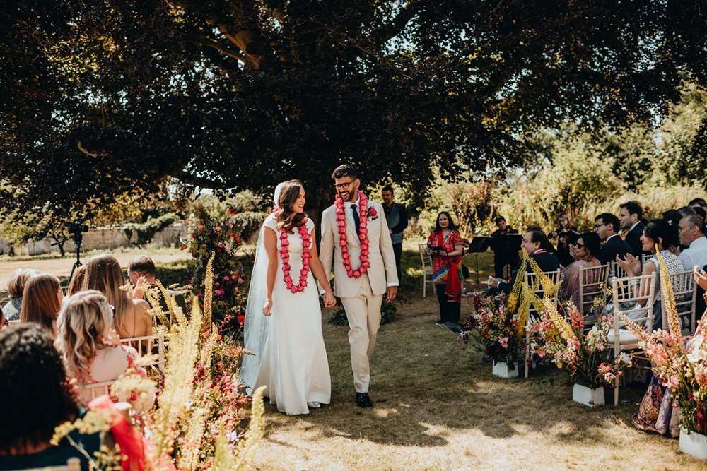 outdoor indian wedding ceremony next to a magnificent stately home on the lawn in summer