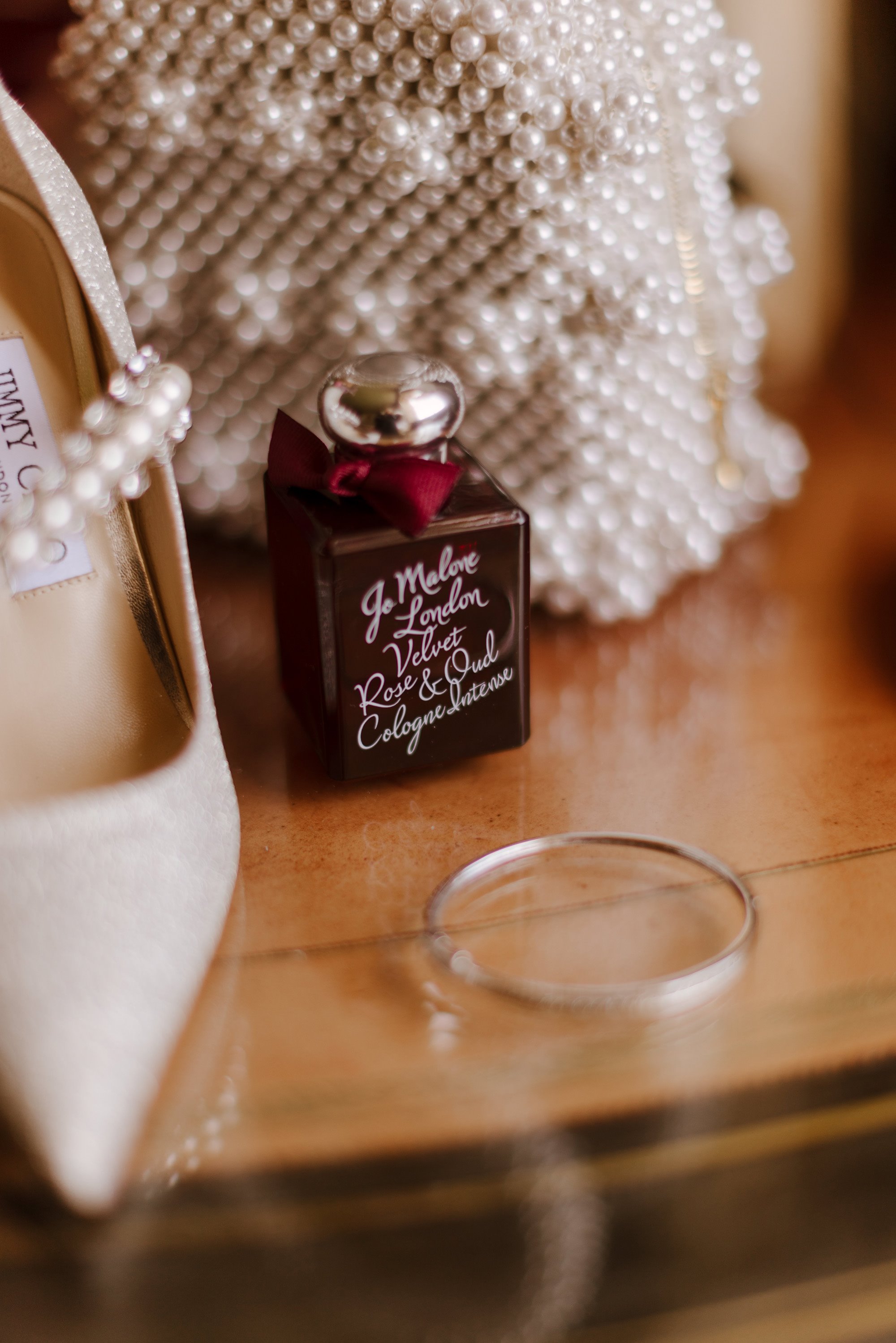 Jimmy choo wedding shoes with pearl strap and pearl handbag by shrimps next to Jo malone perfume bottle on dressing table 