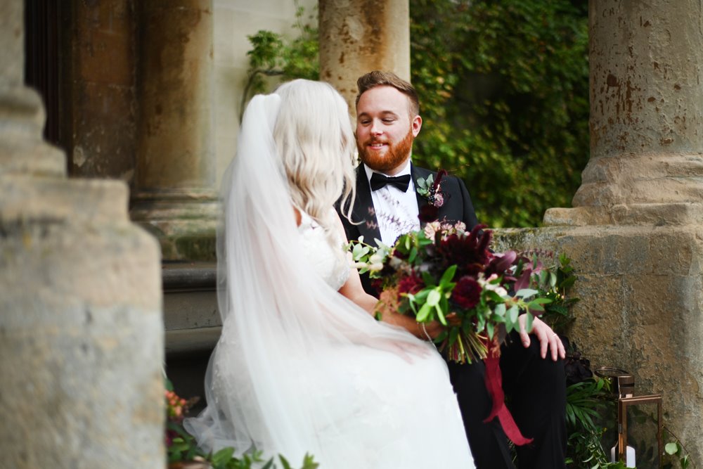 Bride holds dark bouquet for her autumn wedding at stately home venue elmore court