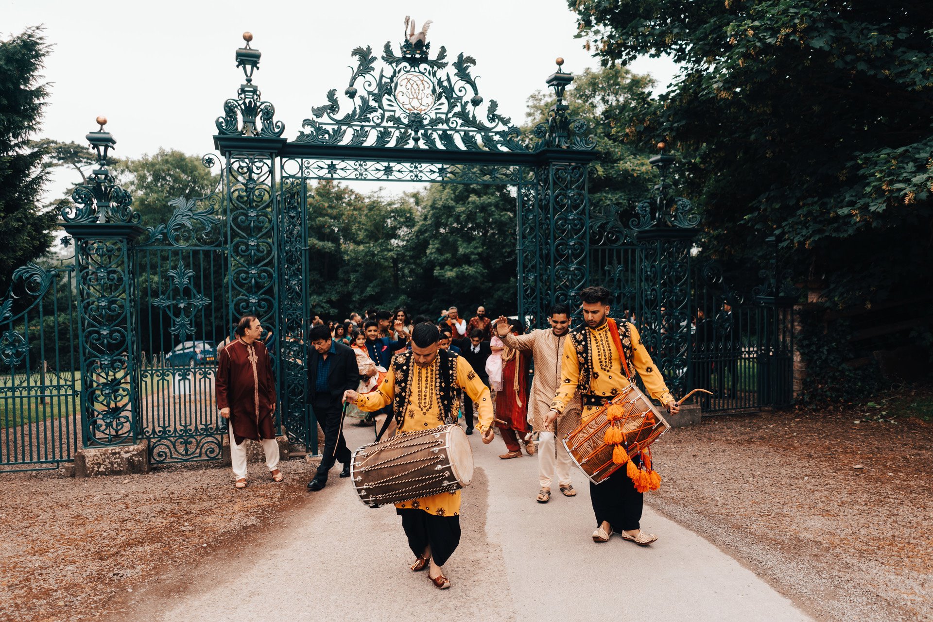 Baraat procession past the wrought iron gates of indian wedding venue elmore court