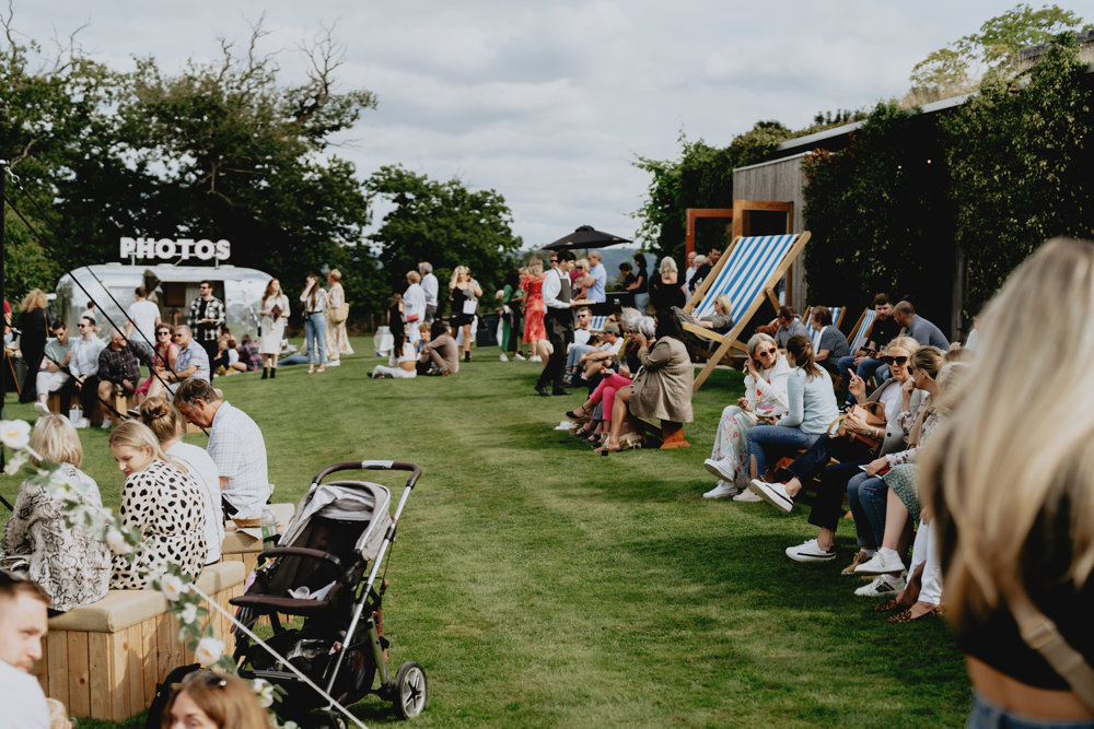 Cool silver trailer caravan photo booth with pink neon lights and bunting at unusual wedding venue elmore court