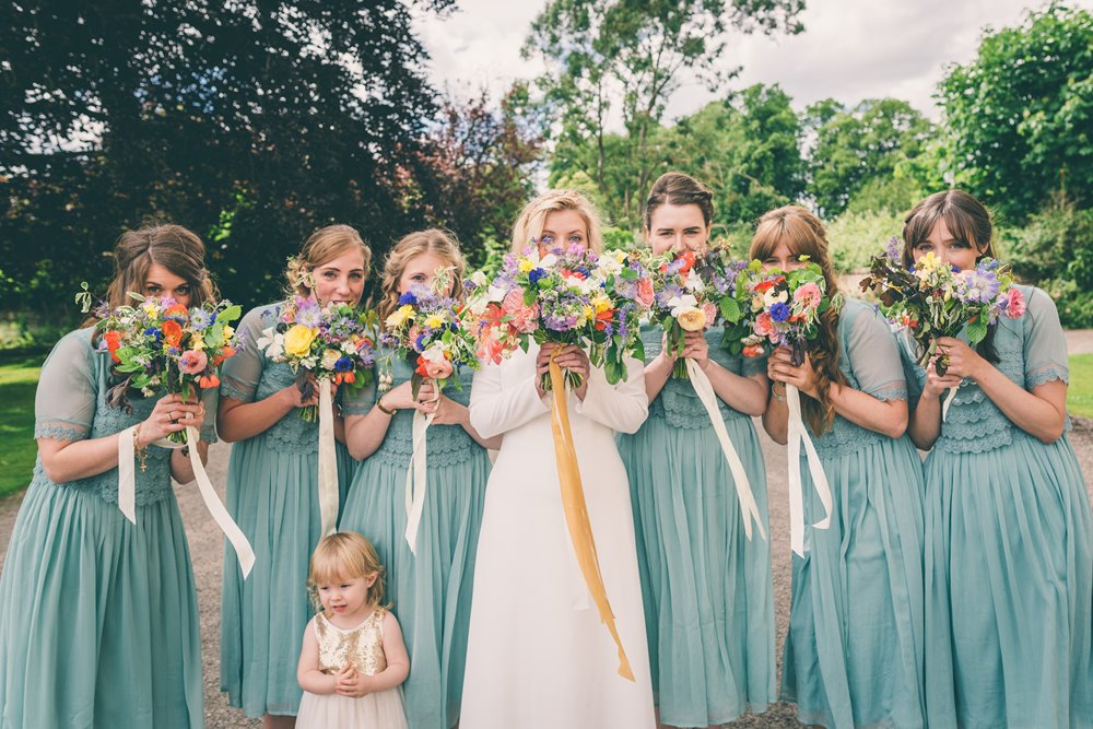 Green bridesmaids trend holding bouquets with ribbons