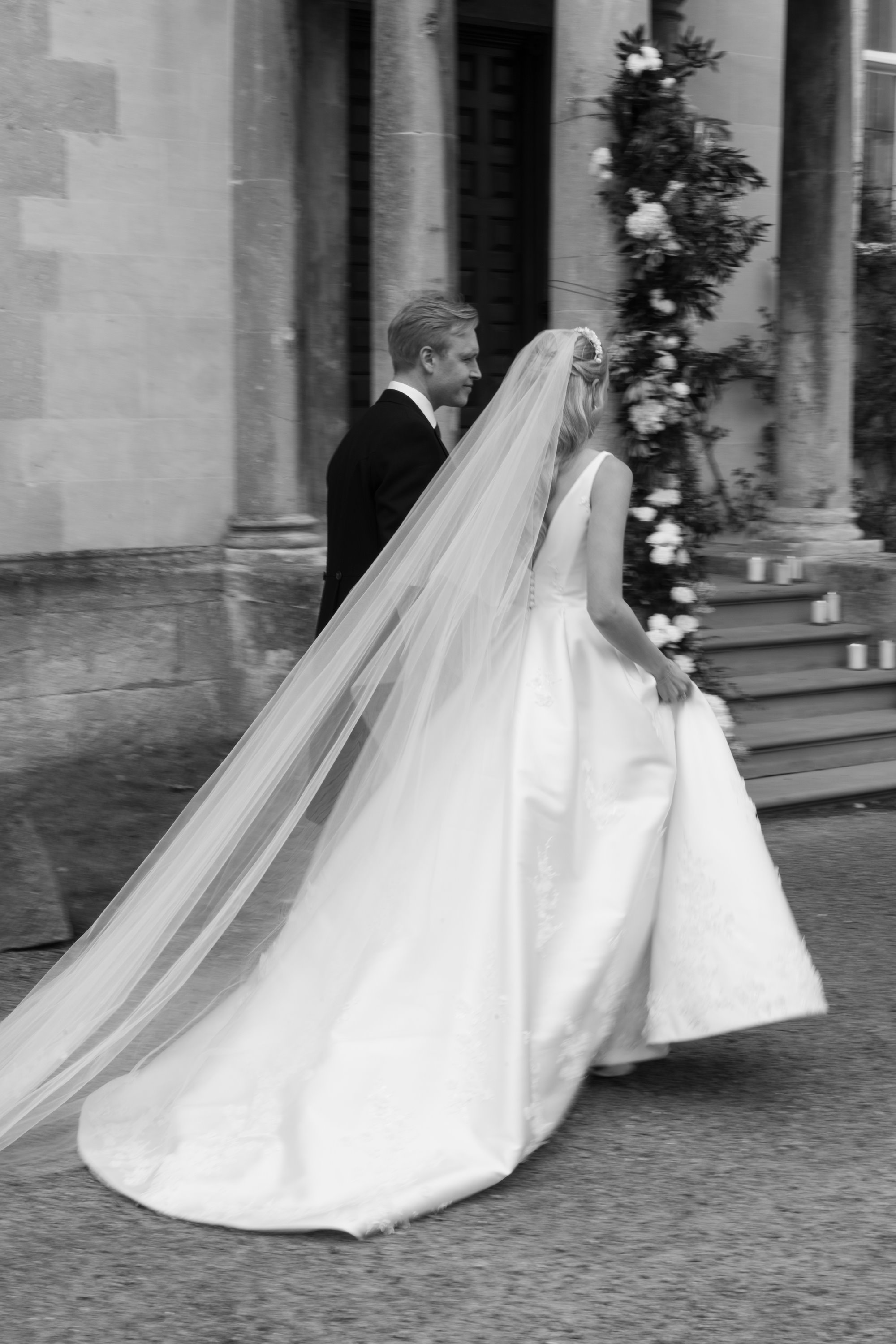 bride with long white veil walking with her new husband