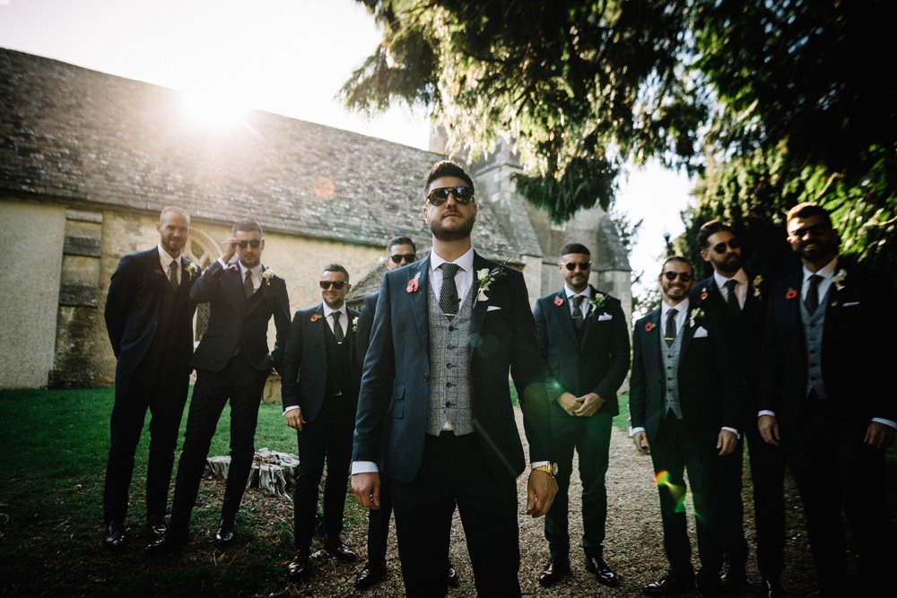 Groomsmen in sunglasses and suits looking very cool outside Elmore church before a wedding ceremony in Gloucestershire