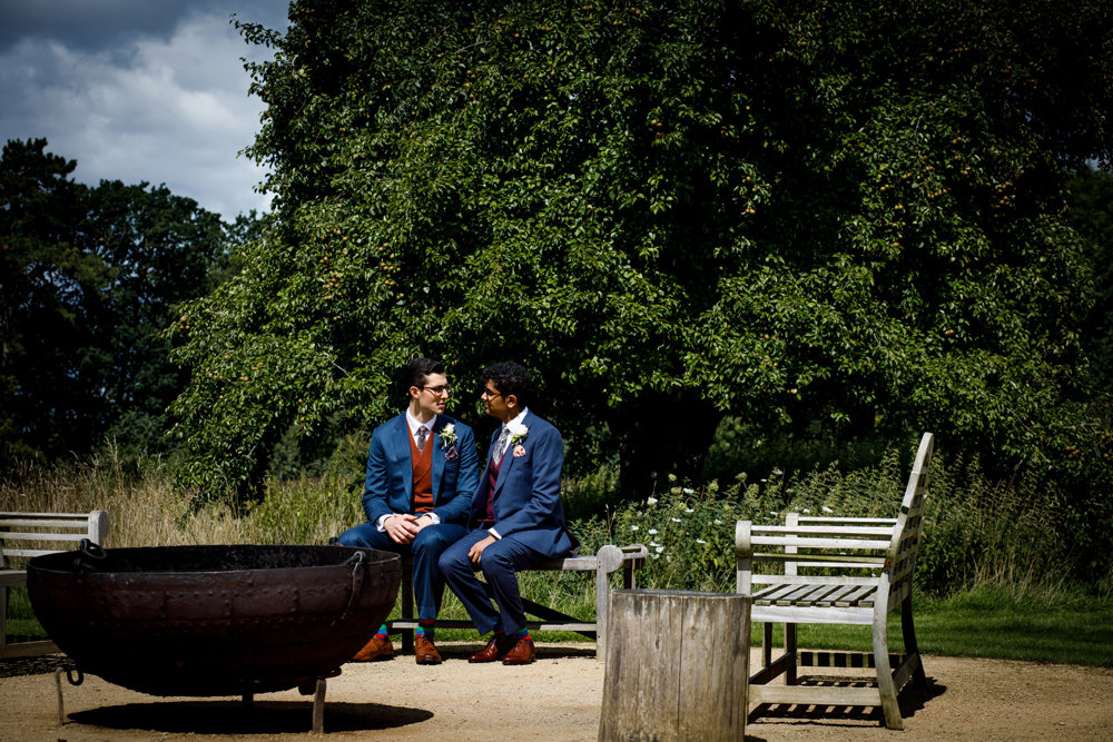 Gay couple pose for photos after their wedding ceremony by the fire pit