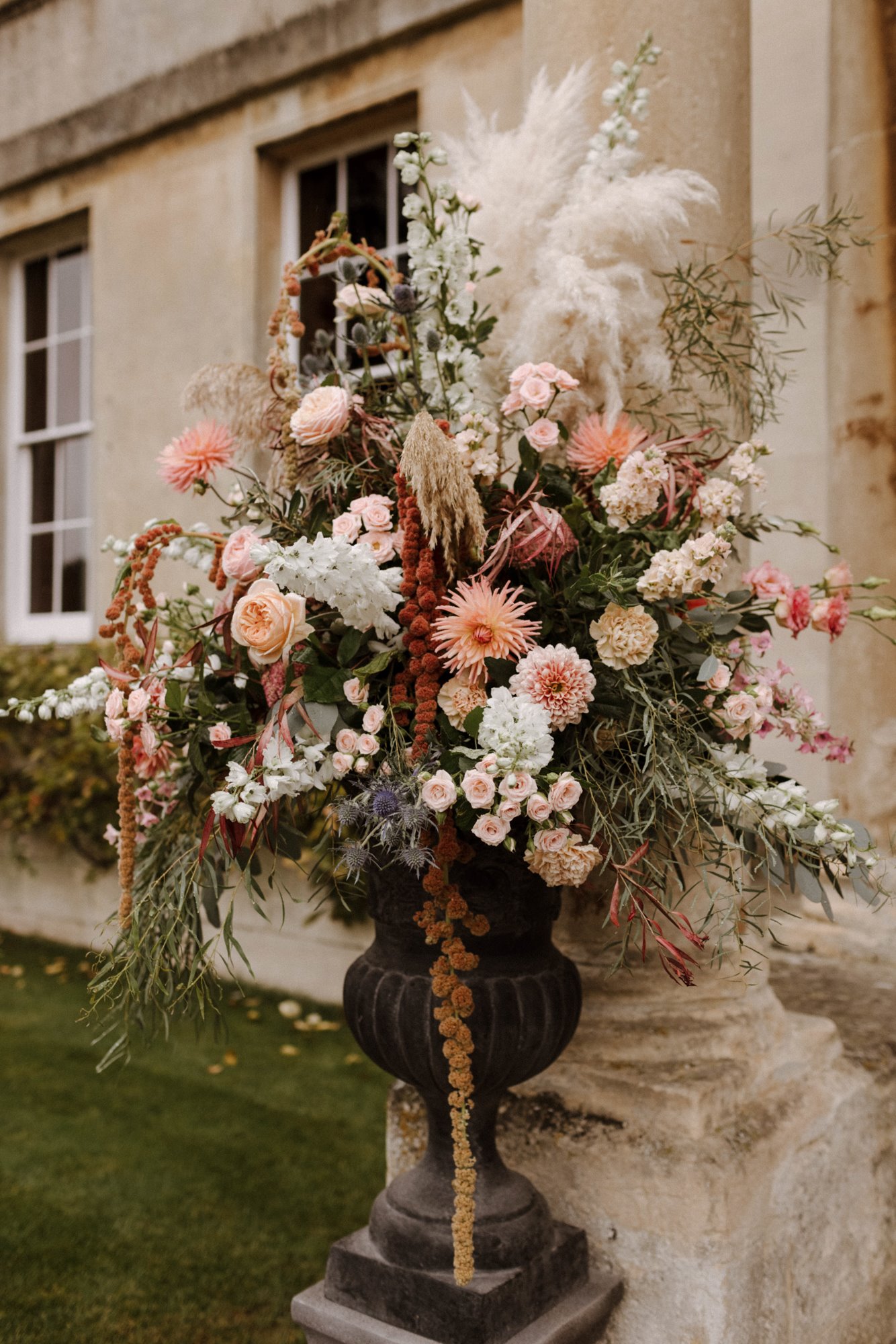 Boho luxe wedding floral displays in urns outside stately home