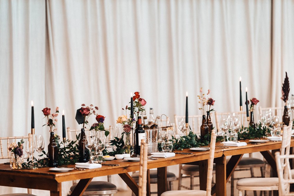 Long tables decorated with black candles and flowers for an elegant dark and moody halloween wedding in the cotswolds
