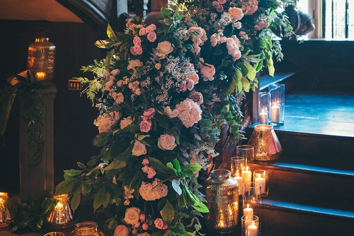 Romantic wedding stairway with roses, greenery and candles decorated up an old staircase in a stately home