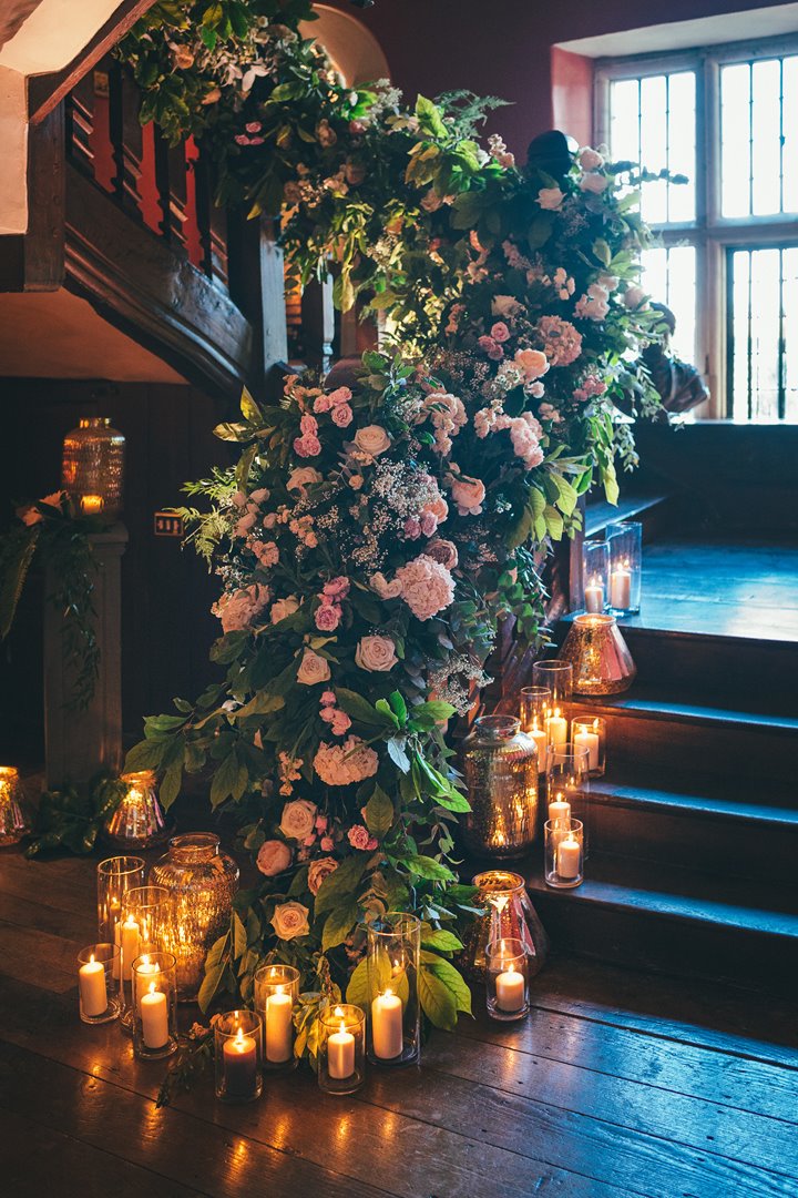 Romantic wedding stairway with roses, greenery and candles decorated up an old staircase in a stately home