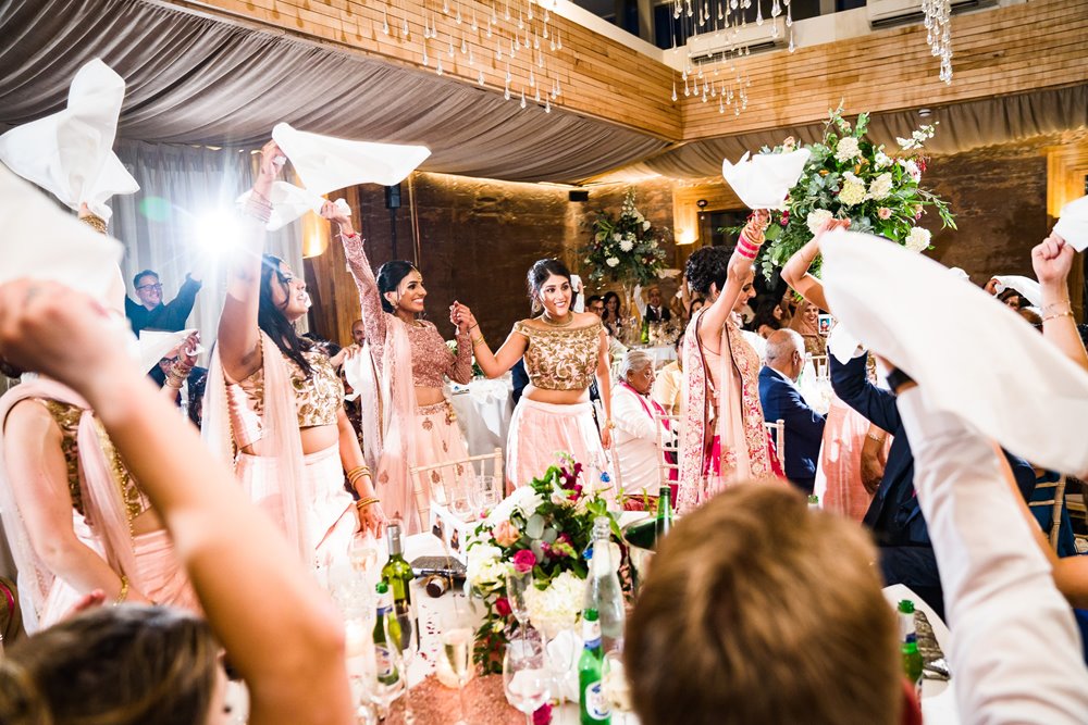 Indian bridal party dancing with napkins at their reception 