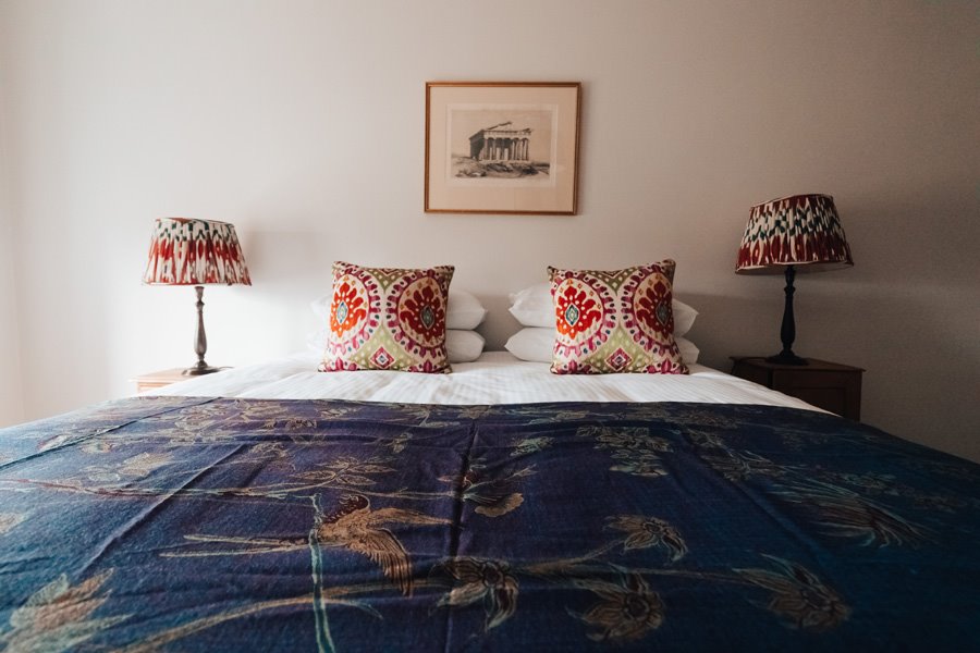 Unique and beautiful bedroom in wedding venue with indian throw cushions and lampshades by Shibumi