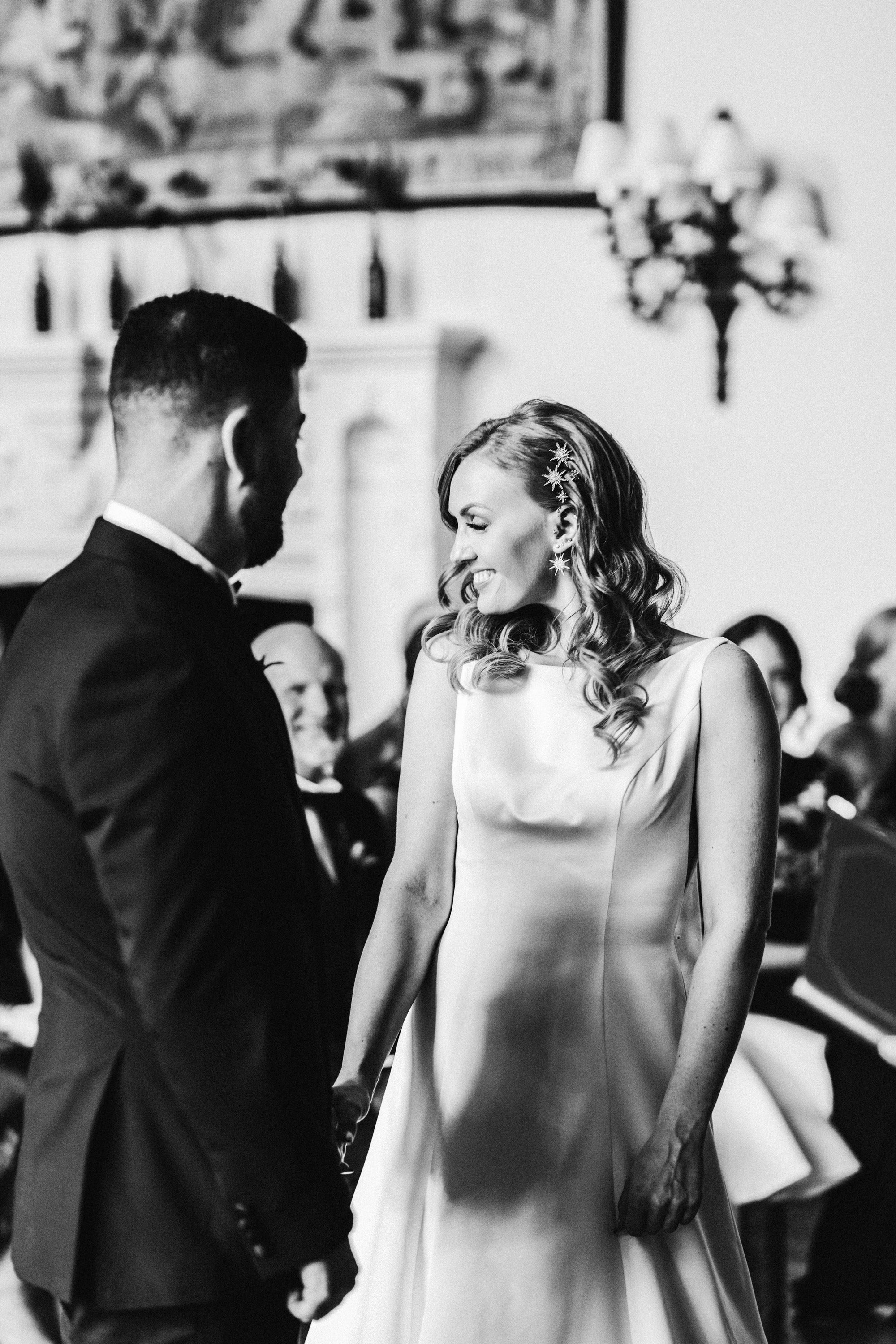 happy bride smiles at guests wearing starry hair clips at glamorous and moody wedding ceremony in the cotswolds